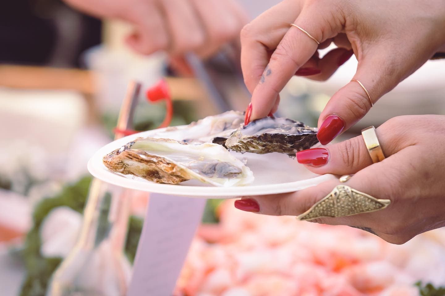 A guest lifting an oyster from a plate